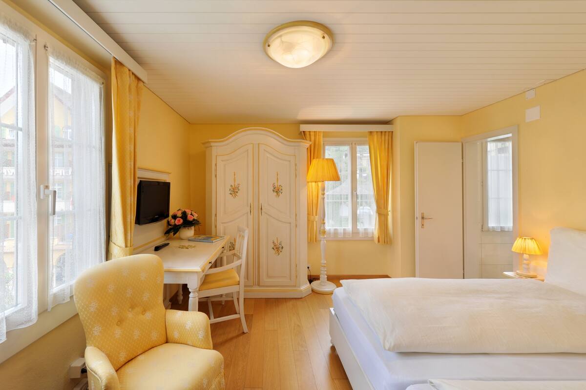Une chambre d’hôtel comprenant un lit, un bureau avec une chaise, une armoire et un téléviseur.
