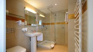 Une salle de bain moderne équipée de toilettes, d’un lavabo et d’une douche à parois de verre.