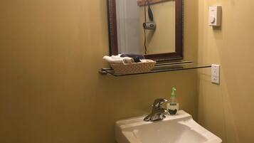 Une salle de bain équipée de toilettes, d’un lavabo, d’un miroir et d’un sèche-cheveux fixé au mur.
