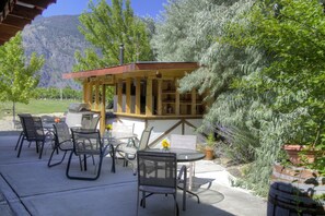 Une terrasse extérieure dotée d’une structure en bois, de sièges et d’un barbecue.