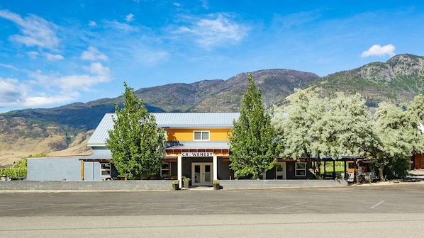 A building named 'Crowsnest' with a parking lot in front, surrounded by mountains and trees.
