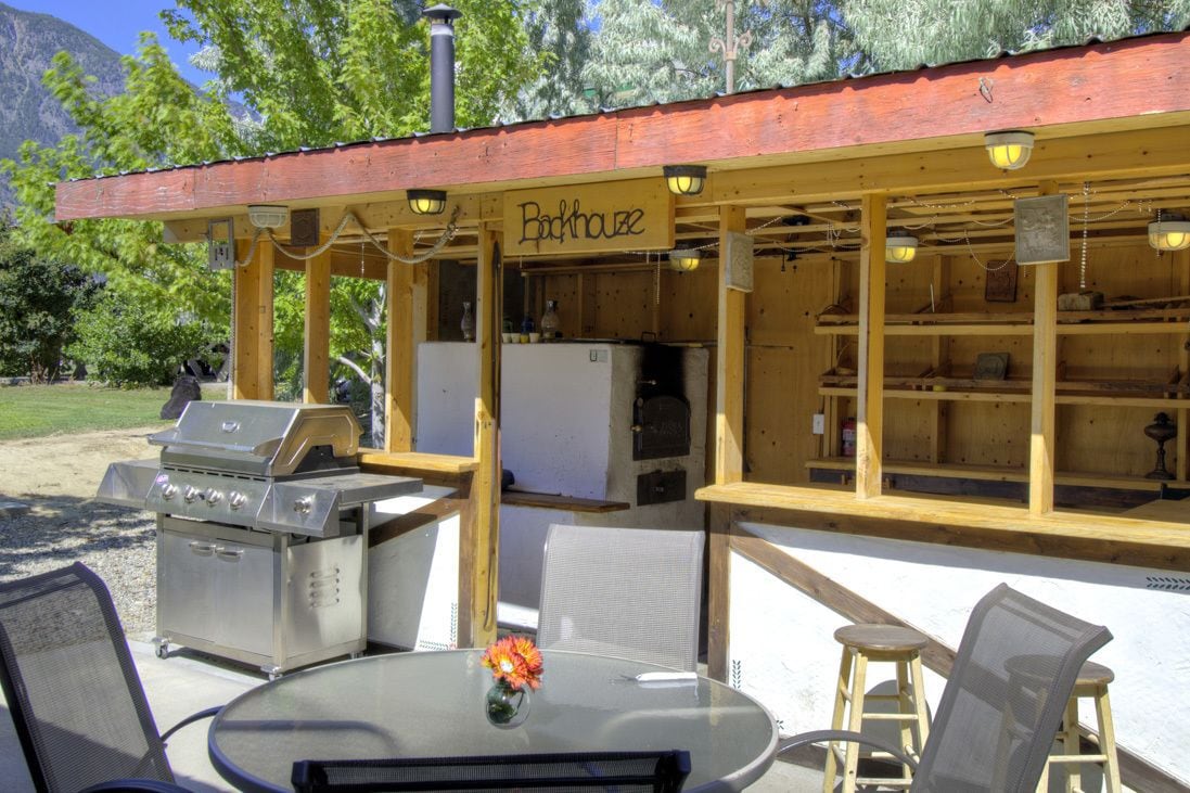 An outdoor barbecue area with a grill, seating, and a sign reading "Backhouse."