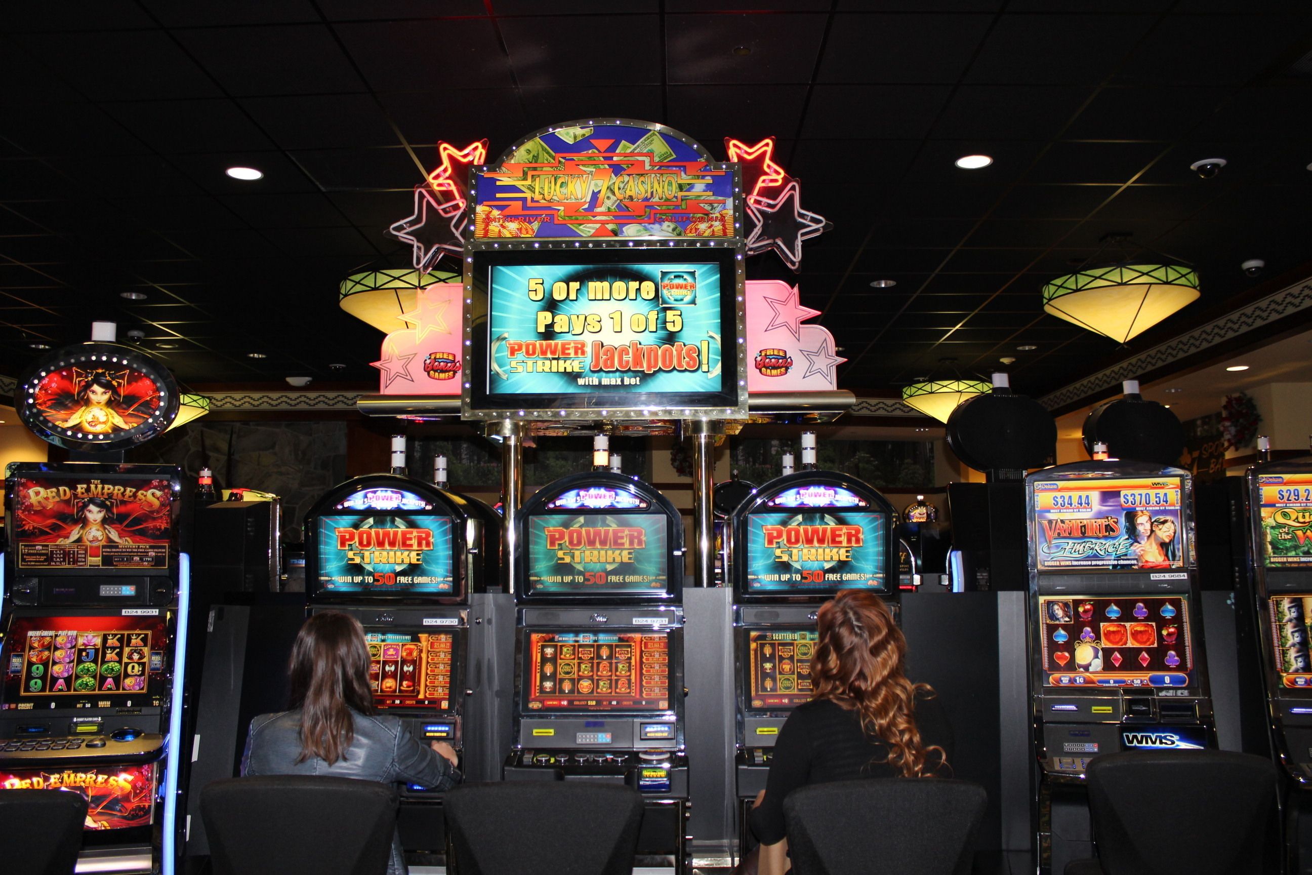A casino with multiple slot machines and a neon sign advertising Power Strike jackpots.