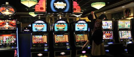 A casino with multiple slot machines, a neon sign, and a chandelier.