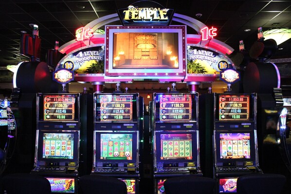 A slot machine area with multiple machines, each displaying different game interfaces and prize amounts.