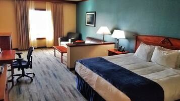 A hotel room with a bed, desk, chair, and a window with curtains.
