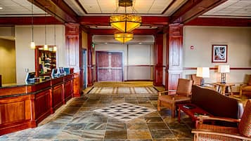 A lobby with a check-in counter, seating area, patterned floor, and a large decorative light fixture.