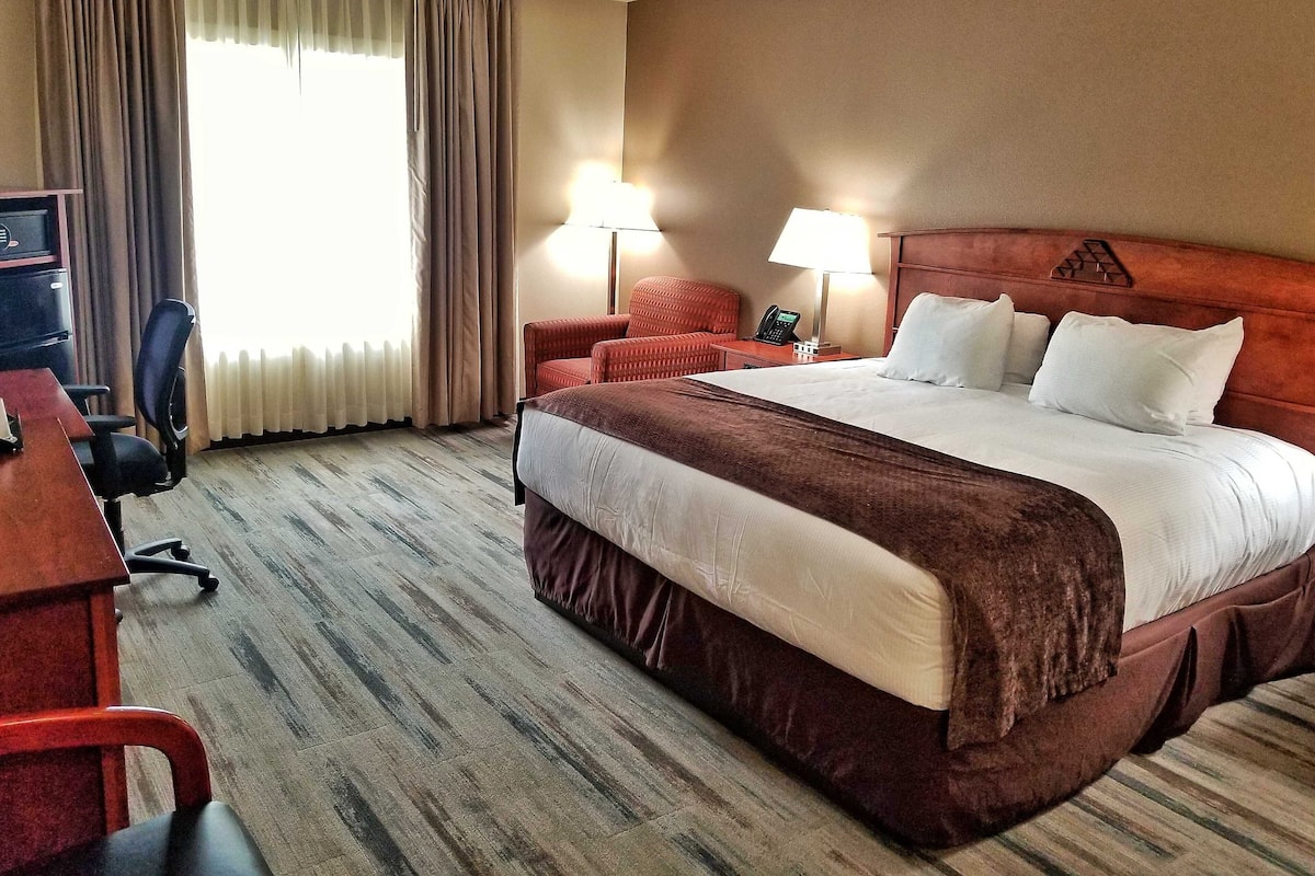 Una habitación de hotel con una cama grande, dos lámparas de noche, un escritorio con una computadora y una silla.