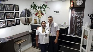A reception area with framed photos on the wall, a clock, and a welcome sign. - Hotel Recanto das Perdizes (São Paulo)