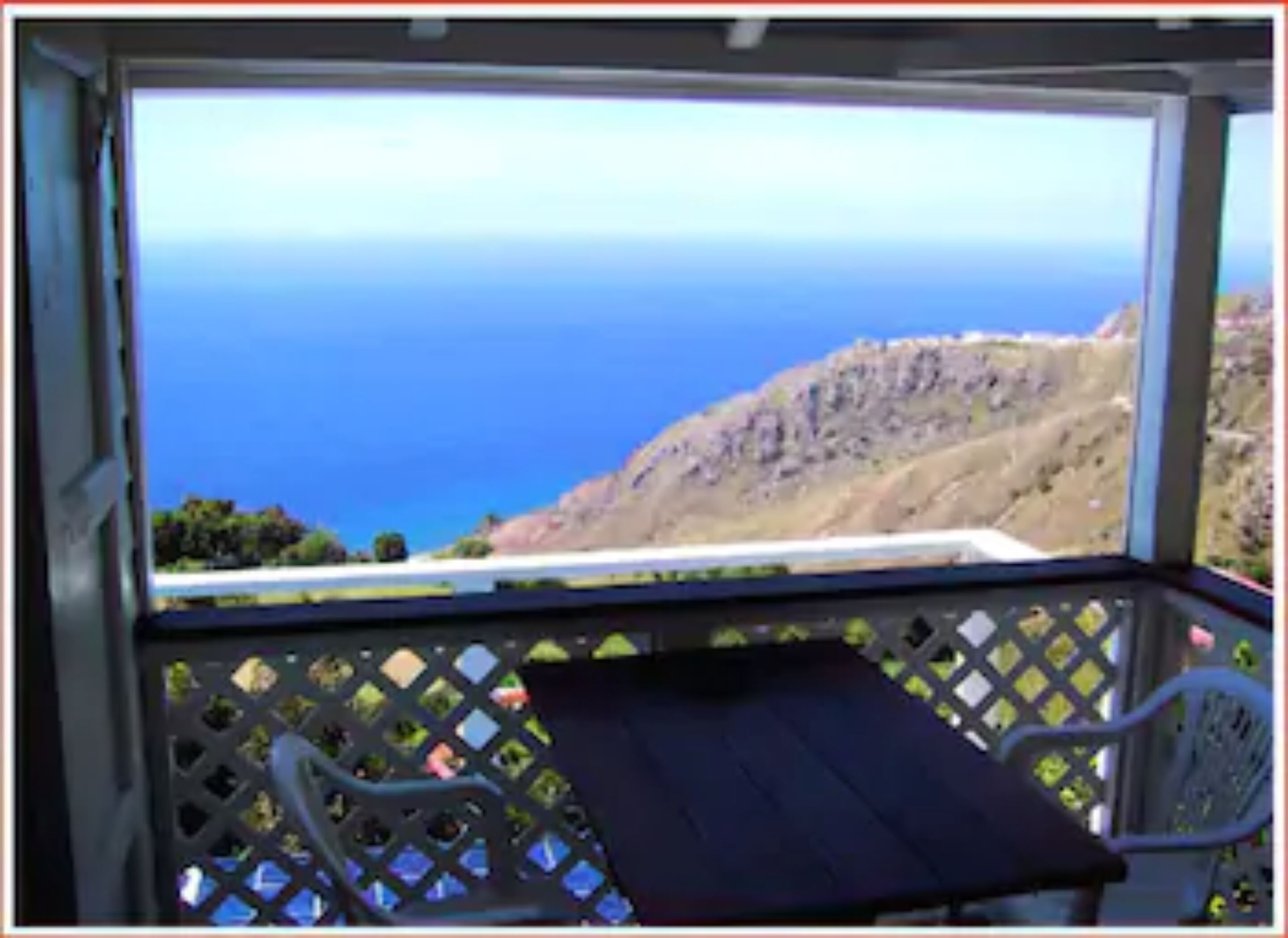 A balcony with a view of the ocean and a rocky hillside.