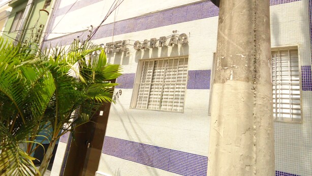 Un edificio con un letrero que dice "HOTEL CARAÓ" y una ventana con rejas de seguridad.