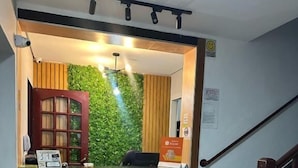 Un área de recepción con mostrador de madera, pared verde y una escalera.