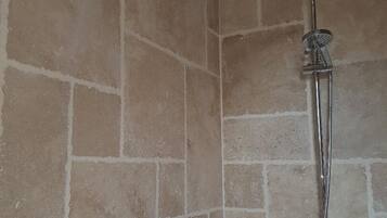 A shower with a handheld showerhead and a wall-mounted control.