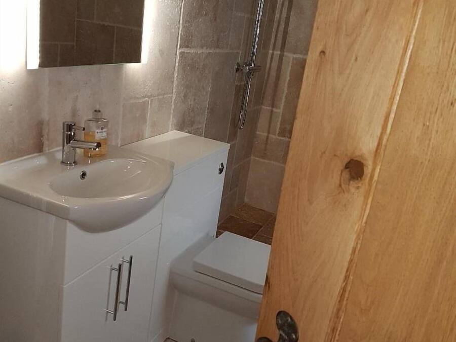 Un baño con lavamanos blanco, espejo y zona de ducha.