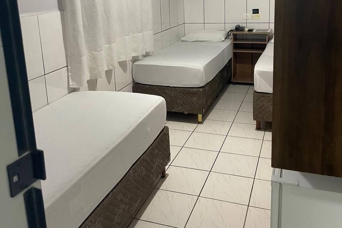 A small, clean bathroom with two single beds, a shower area, and a toilet.