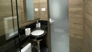 A modern bathroom with a glass shower enclosure, a toilet, a sink with a mirror, and a towel rack. - Hotel Diamantina Av. Brigadeiro Bela Vista SP (São Paulo)