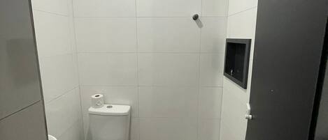 Un baño pequeño con inodoro, ducha y lavamanos.