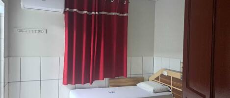 Una habitación con dos camas, un ventilador de techo y una cortina roja.
