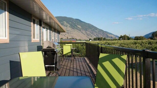 A balcony with a table and chairs, a barbecue grill, and a view of a mountain. - Klippers Guest Suites (Keremeos)