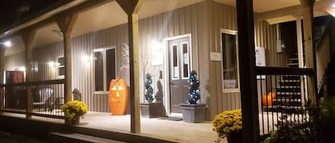 A hotel with a covered porch, a Christmas tree, and a pumpkin decoration.