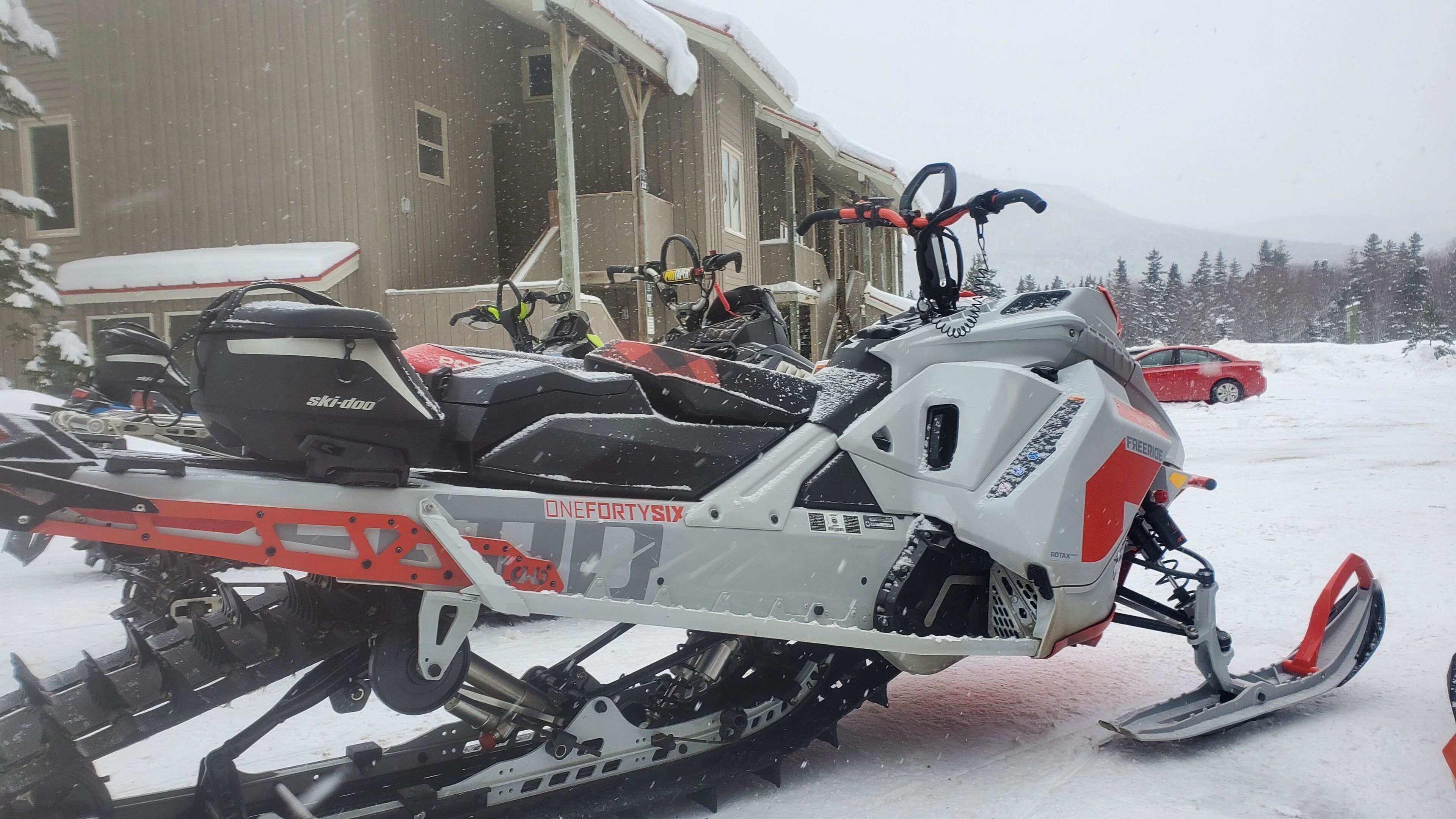 A snowmobile with a red and white frame parked in front of a building.