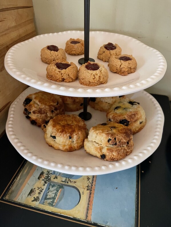 A three-tiered white plate stand with cookies and scones. - Homer Stay and Play (Homer)