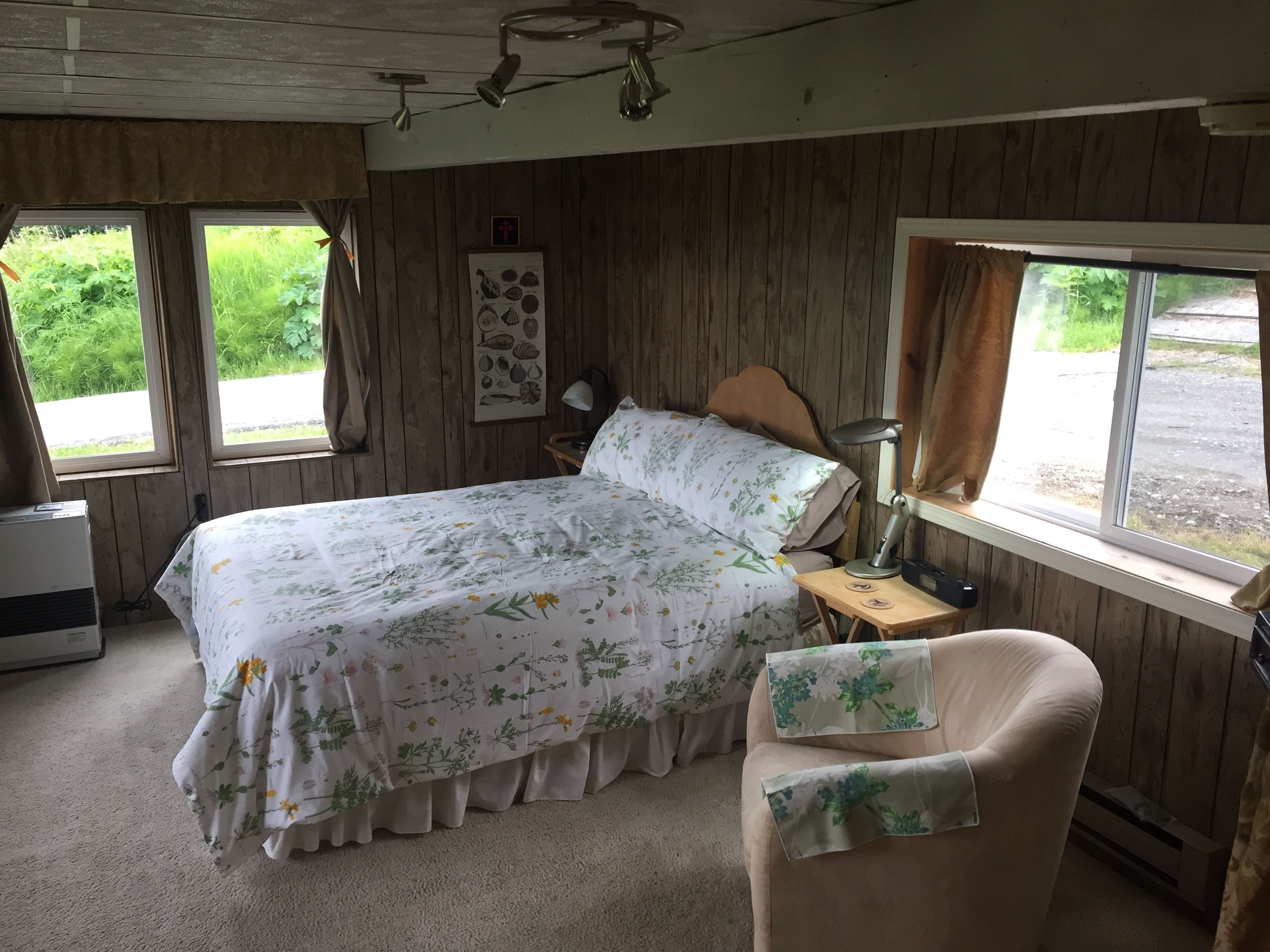 Un dormitorio con una cama, una silla, un escritorio, una lámpara y una ventana.