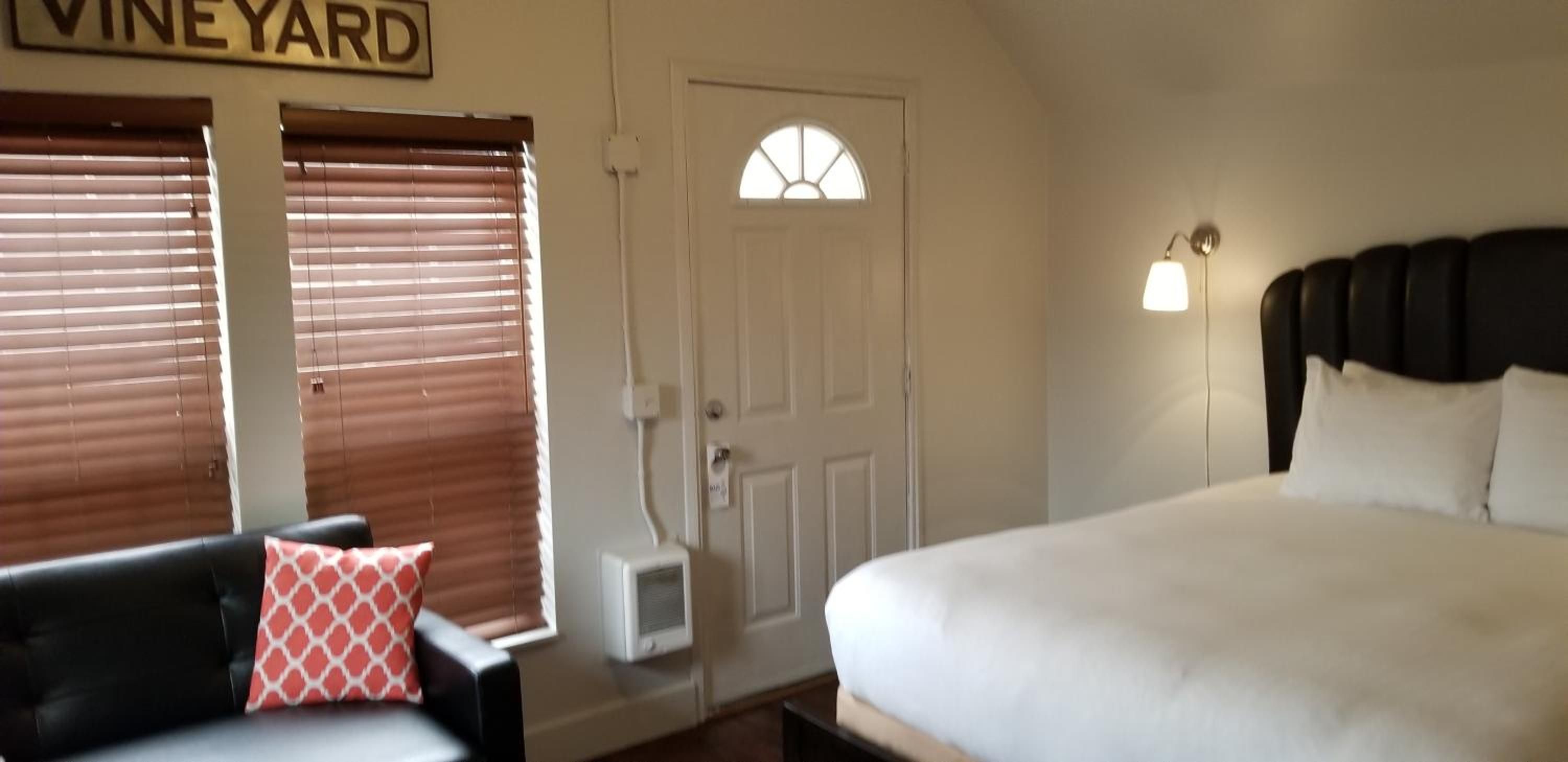 Un dormitorio con una cama, una silla, una puerta y una ventana con persianas.
