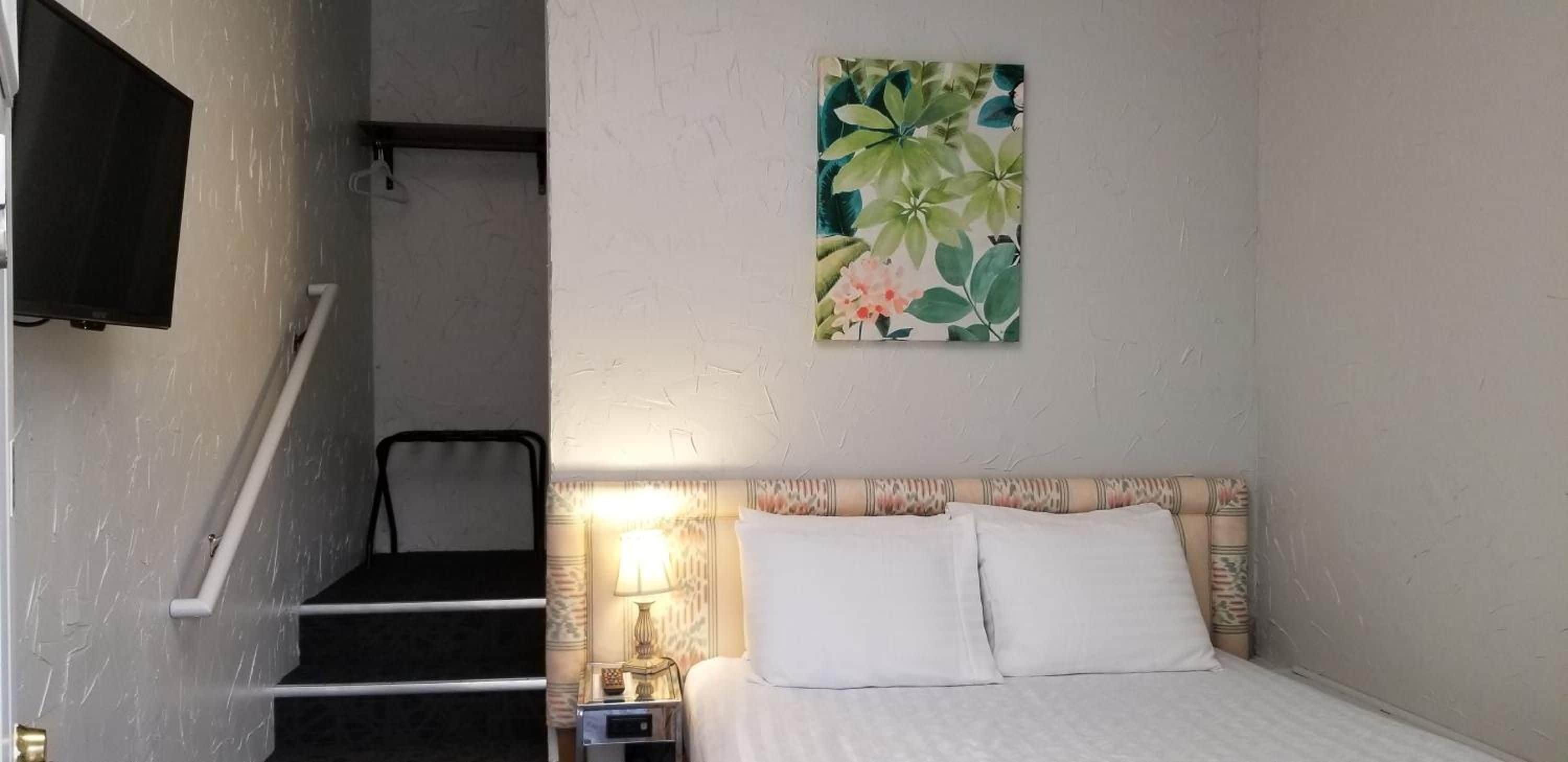 Une chambre d’hôtel avec un lit, une table de chevet, une lampe, un tableau et un escalier.