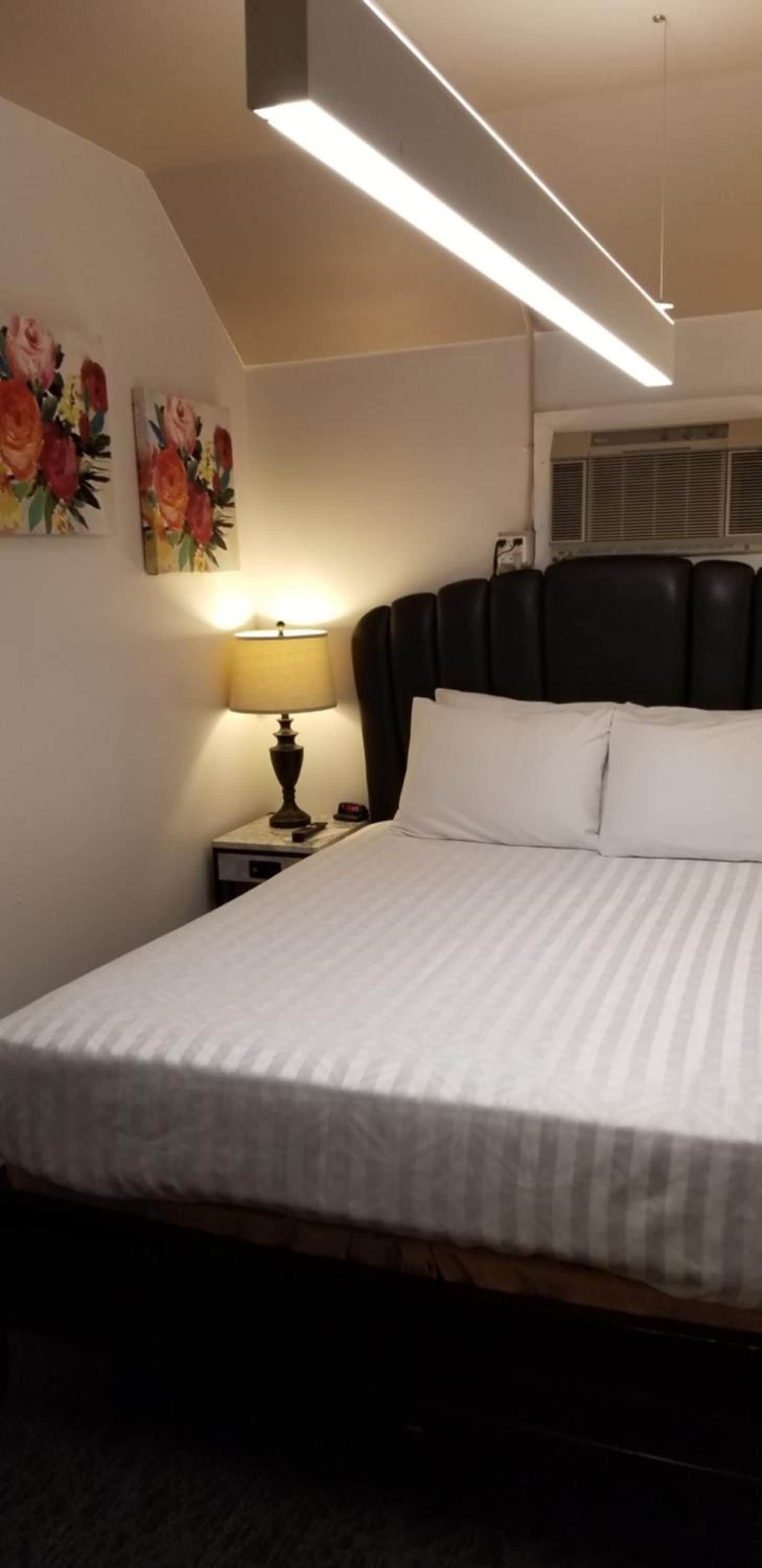 Une chambre d’hôtel avec un lit, une table de chevet avec une lampe et un tableau au mur.
