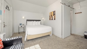 A bedroom with a bed, bedside table, lamp, and a wall art piece. - Deep Water Inn (Chelan)
