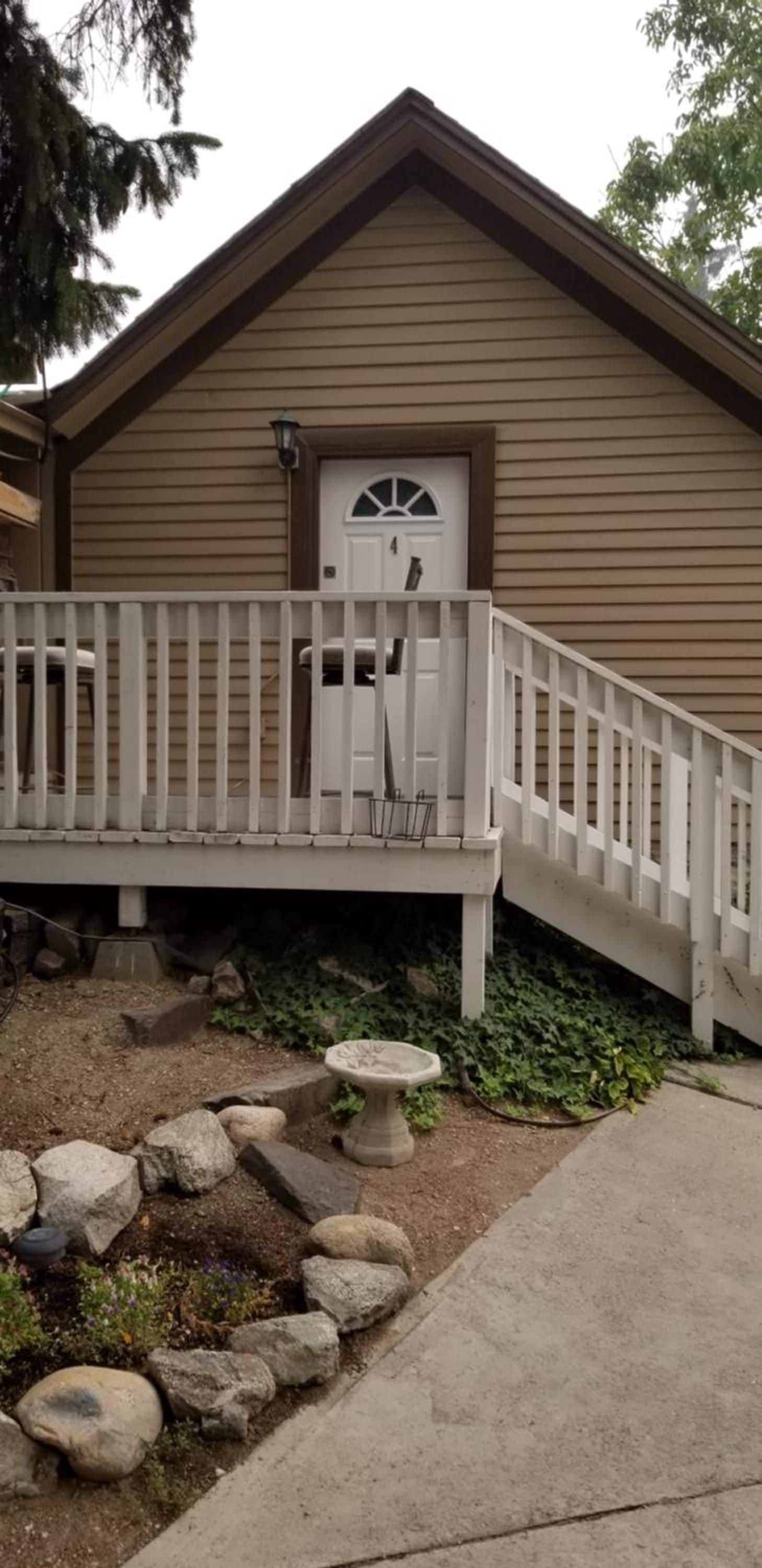 A single-story building with a front porch, a door with a window, and a stone birdbath.