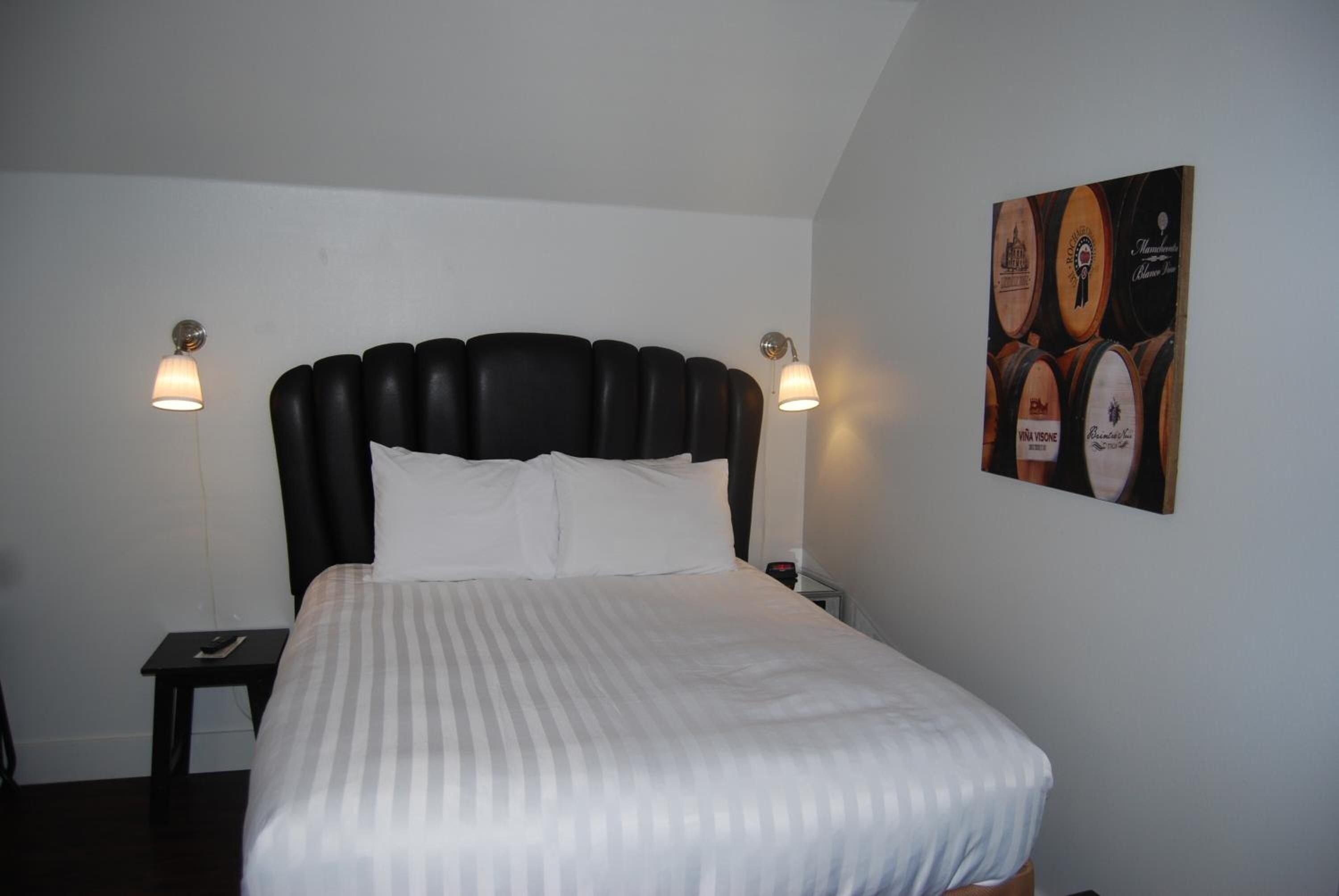 A single bed with a black headboard and white bedding in a room with two bedside lamps.