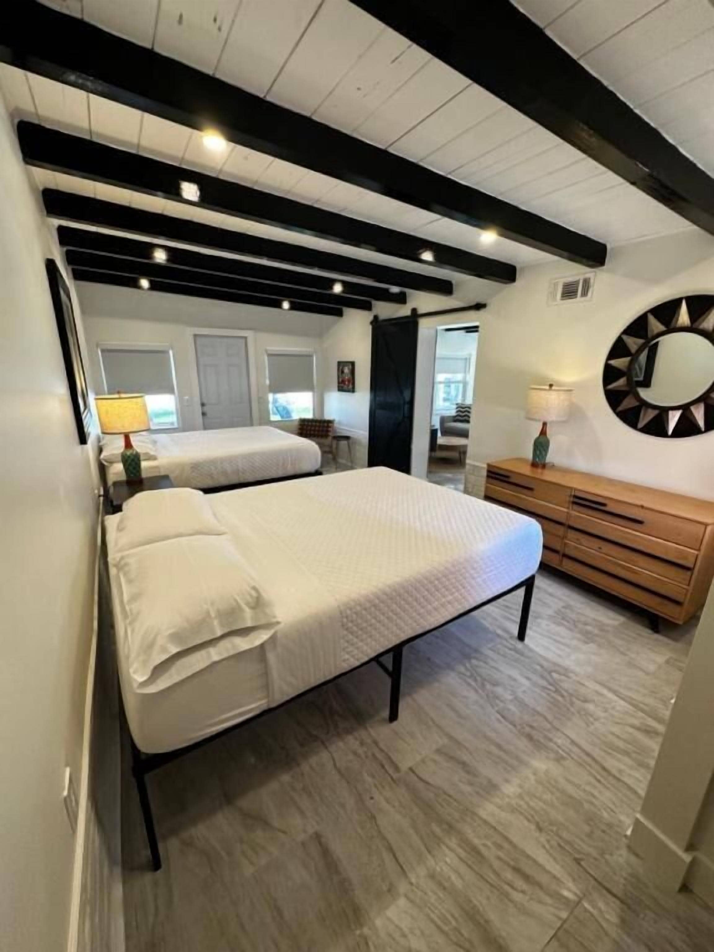 Ein Schlafzimmer mit einem Bett, einer Kommode und einem runden Spiegel an der Wand.