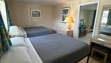 Ein Hotelzimmer mit zwei Betten, einem Schreibtisch, einem Stuhl, einer Lampe und einem Spiegel.
