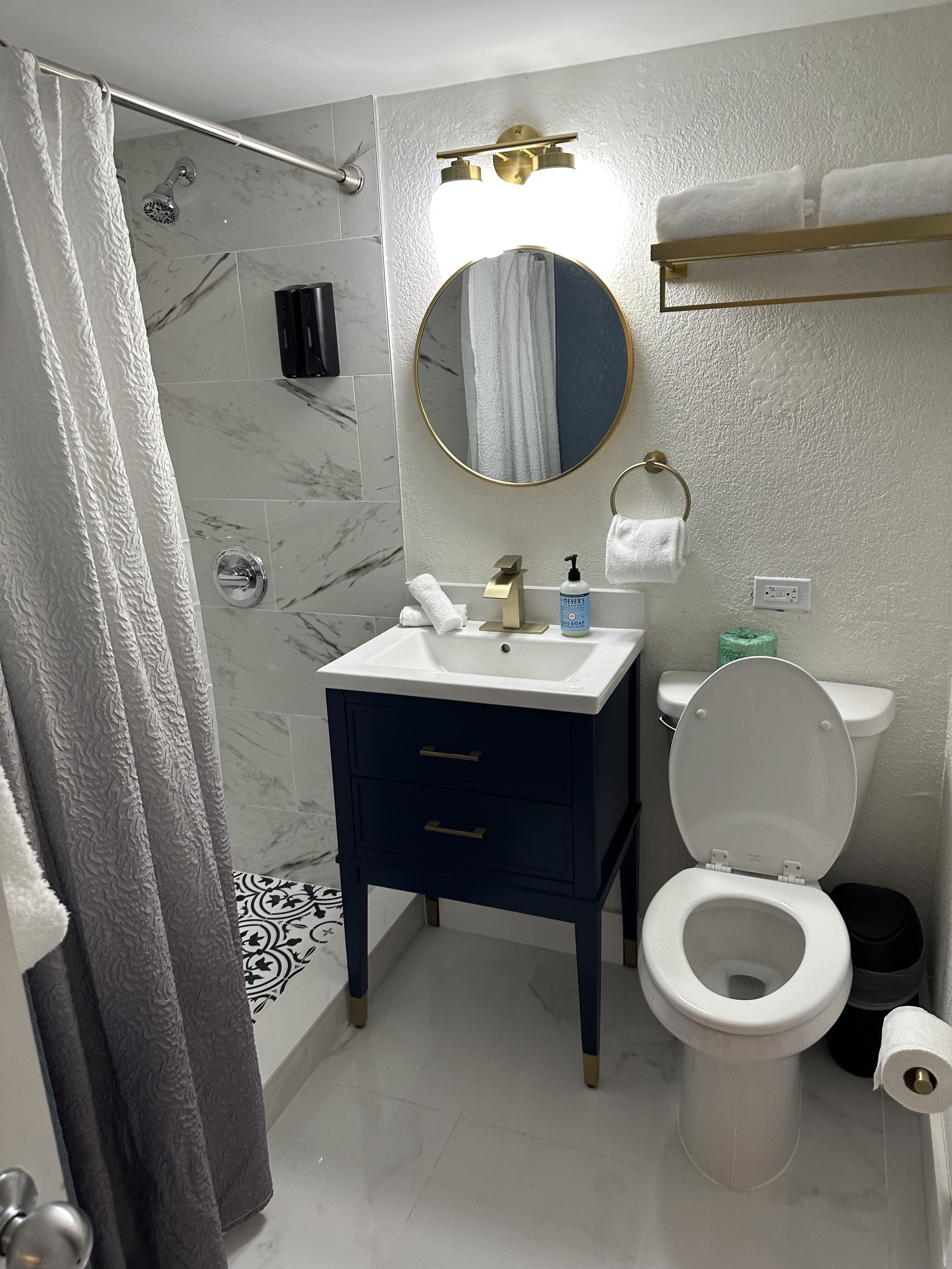 Ein Badezimmer mit Dusche, Toilette, Waschbecken und Spiegel.