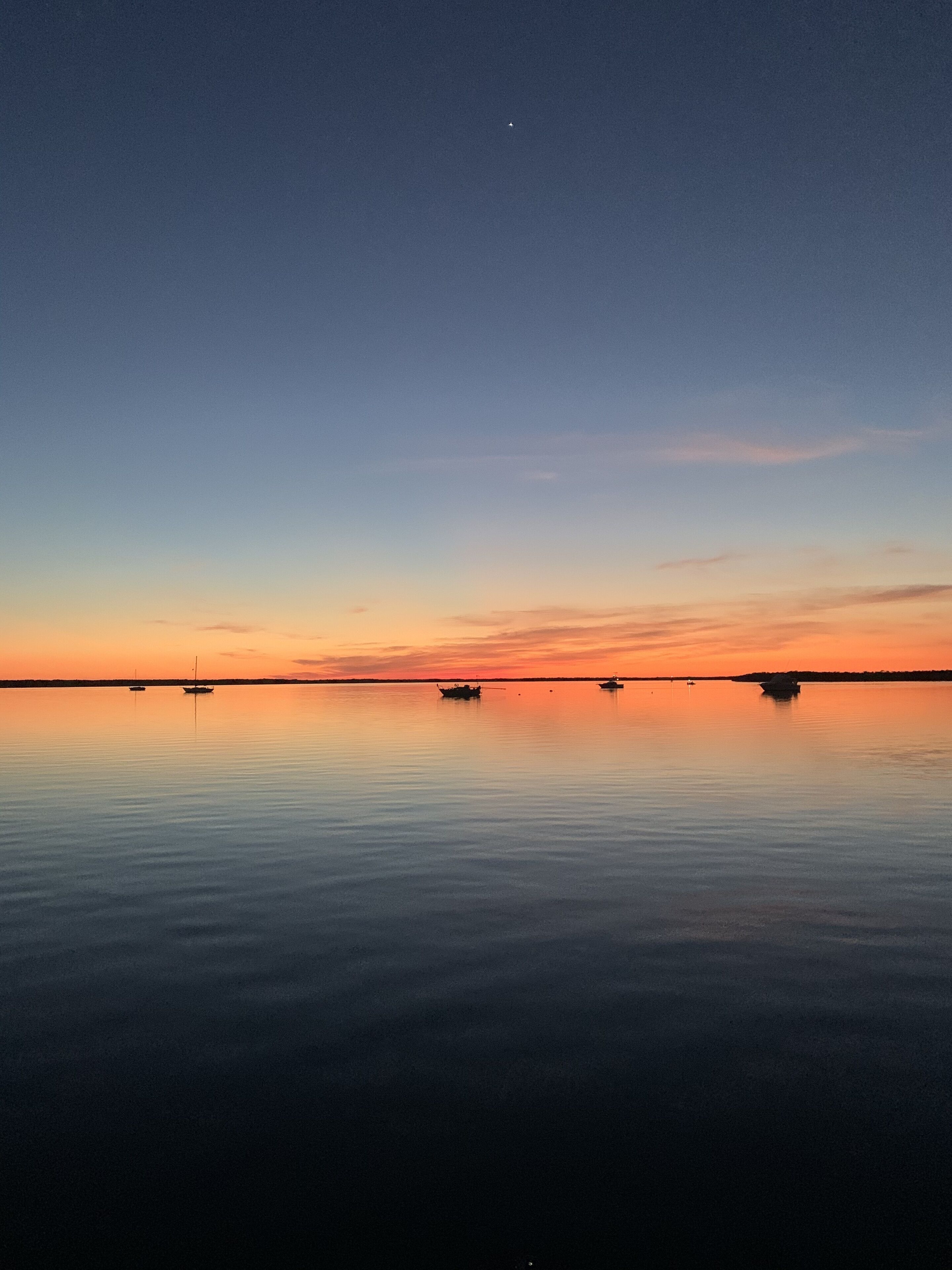 A calm body of water with boats and a clear sky.