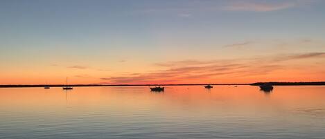 A calm body of water with boats and a clear sky.