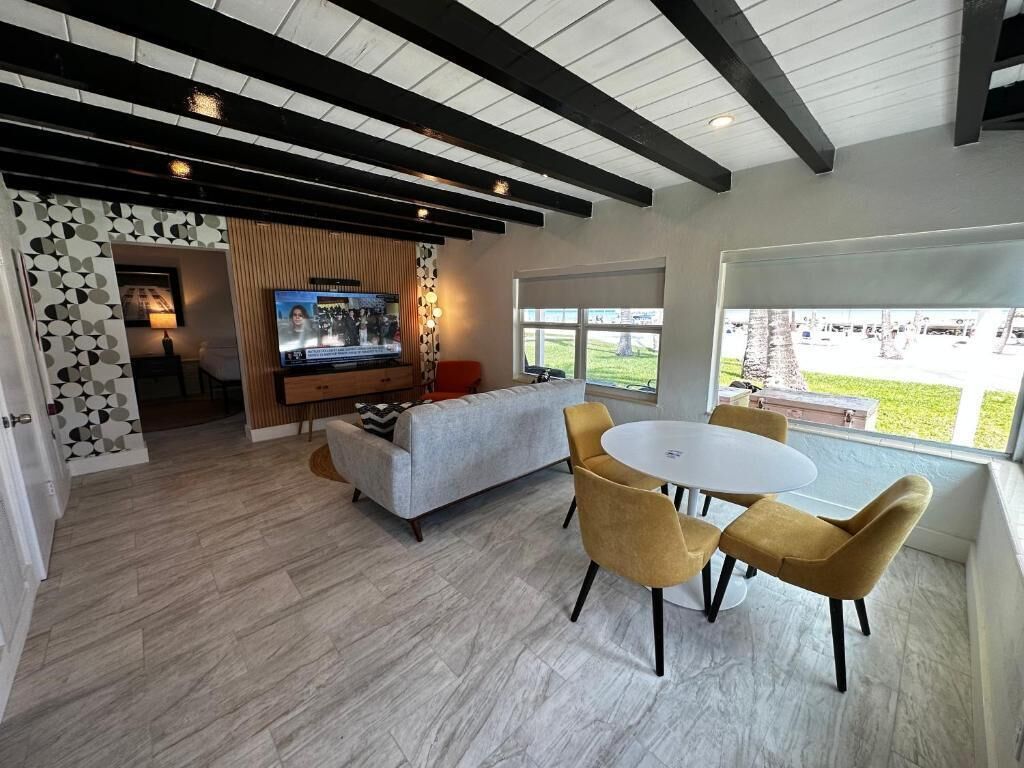 Una sala de estar moderna con televisión, sofá y mesa de comedor con sillas.