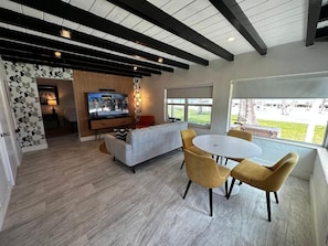 A modern living room with a TV, sofa, and dining table with chairs. - Breezy Palms Resort (Islamorada)