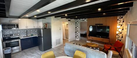 Eine moderne Küche mit Mikrowelle, Herd und Kühlschrank. Ein Essbereich mit Tisch und Stühlen ist ebenfalls vorhanden.
