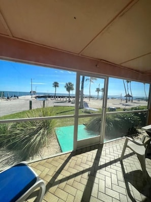 A covered outdoor area with a view of the beach, a pool, and a patio with chairs. - Breezy Palms Resort (Islamorada)