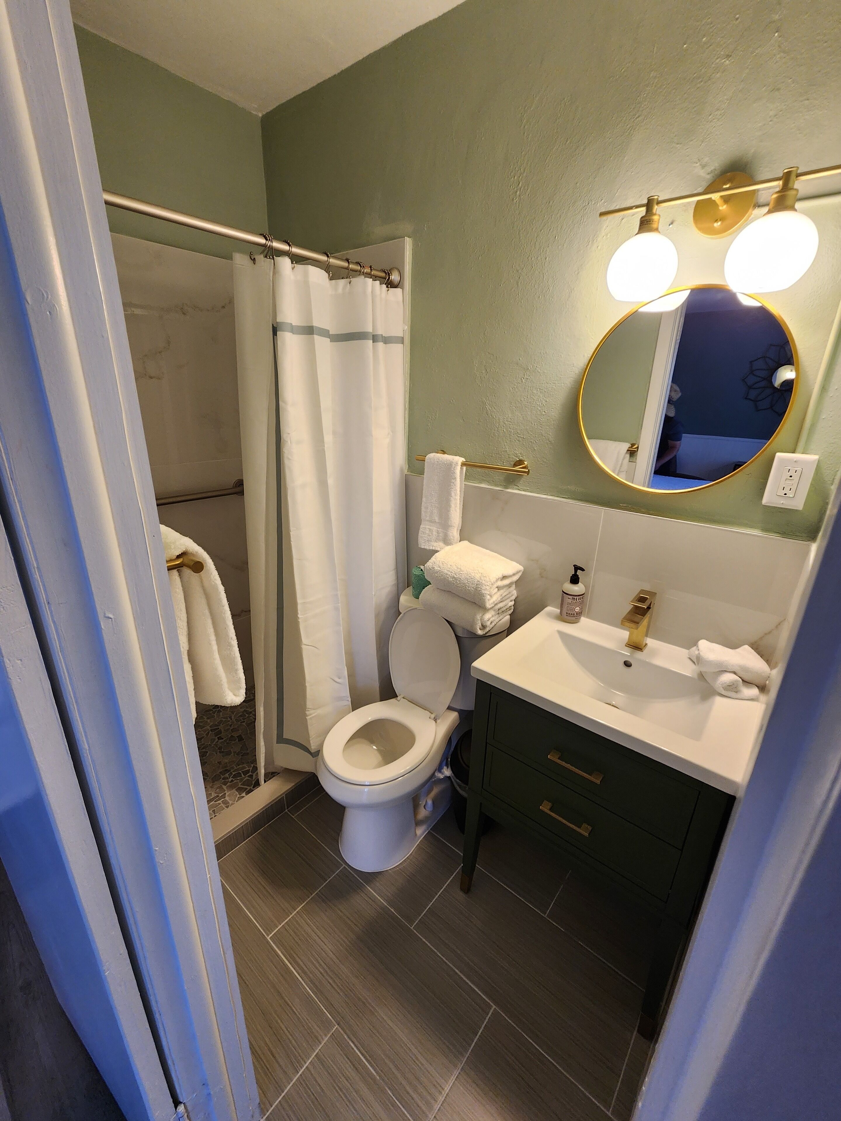 Un bagno con doccia, WC, lavandino e specchio illuminato.