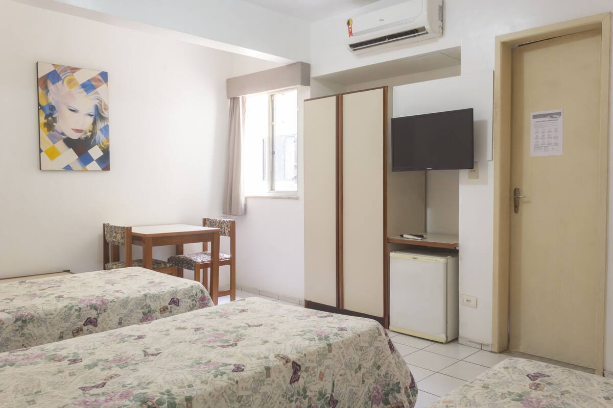 A room with two beds, a desk, a chair, a television, and a wardrobe.