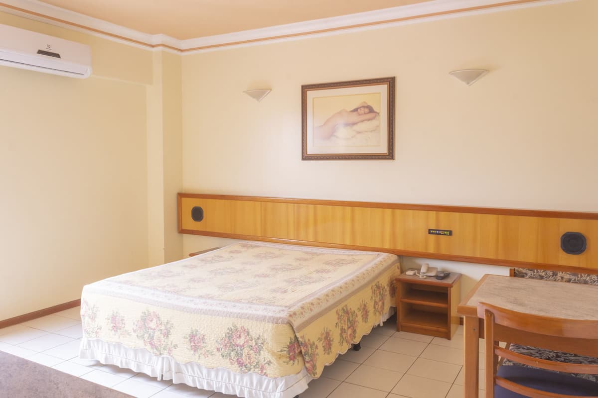 A hotel room with a bed, a small table, and a chair.
