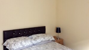 A bedroom with a bed, a nightstand, and a lamp. - The Lodge Guesthouse (Rochester)