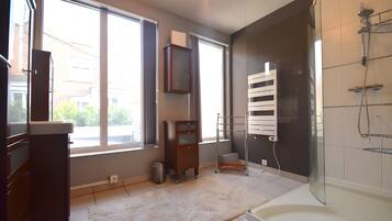 A modern bathroom with a glass-enclosed shower, a built-in toilet, and a large window providing natural light.