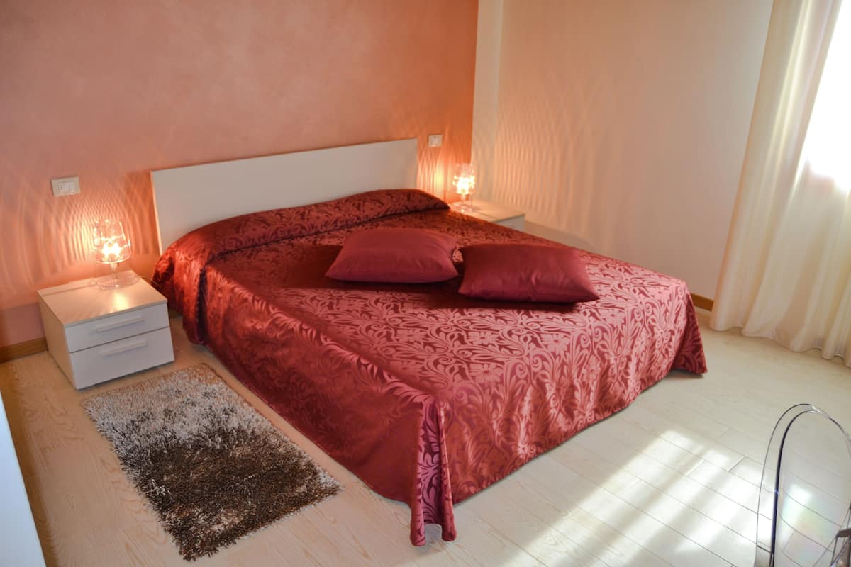Une chambre à coucher avec un grand lit, deux tables de chevet, un tapis et des rideaux.