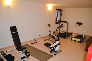 Un gimnasio en casa con una banca, elíptica, cinta de correr y pesas.