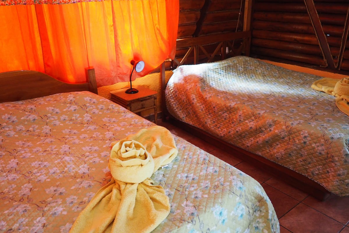 A cozy room with two beds, each with floral bedding and a yellow towel on one bed.